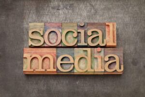 Wooden block letters arranged to spell "social media" on a textured, dark background.