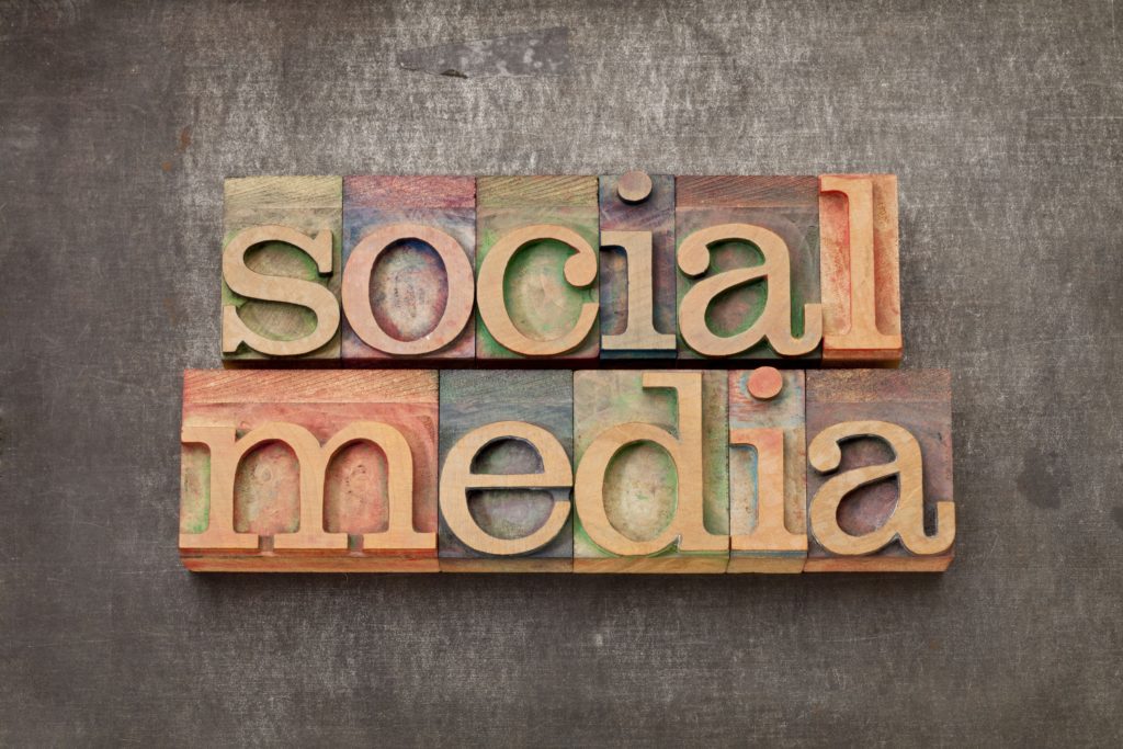 Wooden block letters arranged to spell "social media" on a textured, dark background.