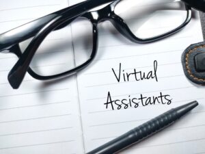 Virtual Assistants written on a piece of paper in black ink with pen and glasses sitting on top of the paper