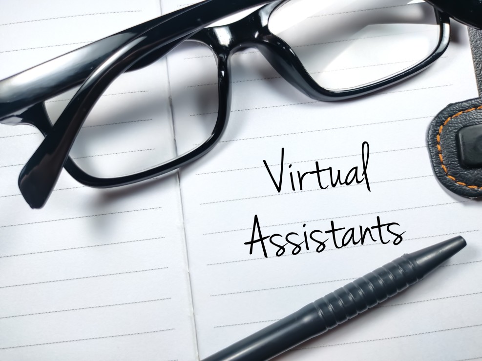 Virtual Assistants written on a piece of paper in black ink with pen and glasses sitting on top of the paper