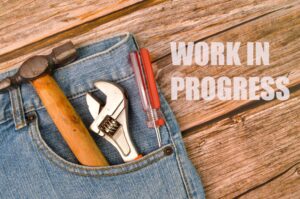 Website maintenance is a work in progress. This is an image of a workman's toolbelt with a hammer, wrench and screwdriver visible. The words Work in Progress is next to it.