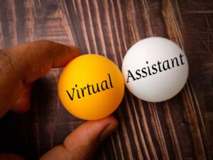 a person holding two golf size balls. One is golden and says Virtual. The other is white and says Assistant